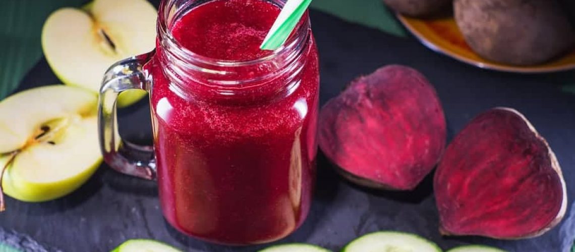 Beetroot smoothie in a mason jar with a straw and ingredients on a wooden background. Fresh beet juice detox. Organic antioxidant smoothies made of beet apple cucumber. Healthy vegan raw food.